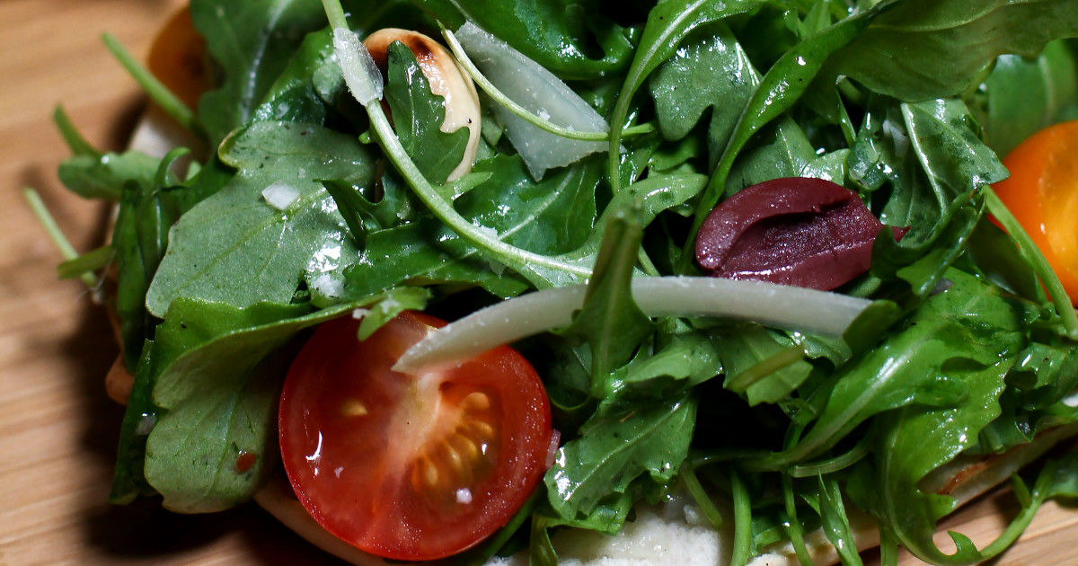 Salade piquante de roquette aux olives noires sur pain plat
